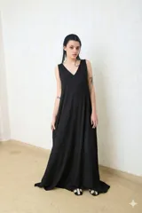 Vestido largo negro, sin mangas, con escote en V pronunciado y corte amplio y fluido.
