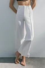 Jeans de tiro alto, pierna ancha y largo al tobillo, en denim celeste claro con efecto lavado. Presenta costura marcada en el centro de cada pierna y cierre frontal con cremallera y botón.