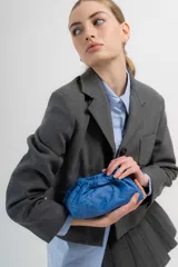 Cartera sobre azul de cuero con frunces y pespuntes diagonales.