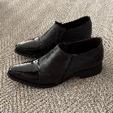 Zapato bajo de cuero vacuno negro con punta fina y detalle de cuero charol en la puntera.