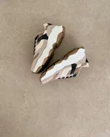 Sneakers de diseño moderno en tonos beige y negro, fabricadas 100% en cuero vegano.