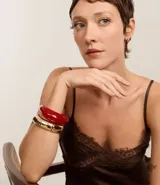 Kit de dos brazaletes, uno rígido de resina color rojo y otro elástico dorado.