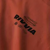 Remera color terracota con logo de la marca Rivvia estampado en el pecho.