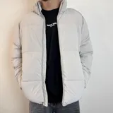 Campera puffer color gris claro, con cuello alto y cierre frontal con cremallera.