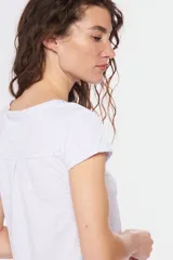 Remera color beige con escote redondo, manga corta, bolsillo en el pecho y cierre parcial con botones.