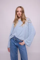 Remera de tejido a rayas celestes y blancas, de lana y algodón, con silueta oversize, cuello redondo y mangas largas anchas.
