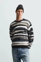 Sweater de punto con cuello redondo y manga larga, con diseño de rayas horizontales en tonos negro, gris y blanco.