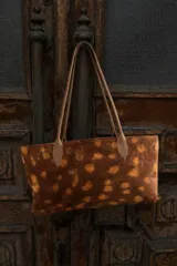 Cartera tipo tote confeccionada en cuero con estampado animal print de manchas. Cuenta con doble asa larga para llevar al hombro.