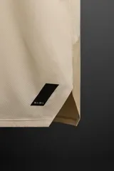 Musculosa deportiva color beige de tejido técnico ligero y elástico con estructura perforada. Tiene cuello redondo amplio, manga sisa con acabados termofijados, bajo con aberturas laterales y logo estampado.