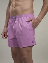 Short de baño verde con estampado de margaritas blancas y cordón ajustable naranja.