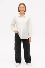 Camisa blanca de algodón con pequeños calados, de corte holgado y manga larga.