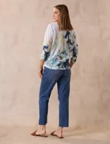 Buzo blanco estampado con flores azules y detalles en verde y amarillo, de la marca Milano. Tiene cuello redondo y mangas 3/4 con apliques de brillos en el frente.