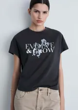 Remera negra de algodón con cuello redondo y mangas cortas. Estampado frontal con la frase "Evolve & Grow" y diseño de mariposas en color blanco.
