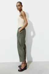 Pantalón capri color verde militar confeccionado en lino, de tiro medio, con bolsillos laterales y traseros. Cierre frontal con cremallera y botón.