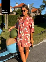 Camisa oversize de manga corta con cuello solapa, confeccionada en una mezcla de viscosa y lino. Presenta un estampado de flores grandes en tonos coral, salmón y blanco roto sobre fondo rosado.