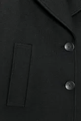 Abrigo corto negro de cuello solapa y manga larga. Tiene bolsillos de vivo en el delantero y cierre frontal con botones.
