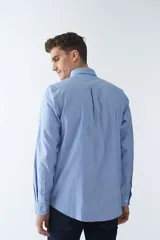 Camisa oxford celeste con rayas verticales blancas, de manga larga y corte regular. Tiene cuello abotonado, bolsillo en el pecho y logo bordado.