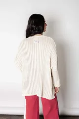 Poncho tejido de punto color crudo con lurex, de calce suelto y relajado.