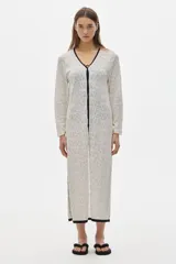 Túnica tipo vestido color crudo, tejido calado, largo midi y cortes a los lados. Tiene cuello redondo y mangas largas.