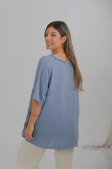 Blusa celeste con estampado de hojas marrones, cuello en V con terminación desflecada y mangas cortas.