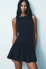 Vestido corto azul marino sin mangas, con cuello redondo, falda fruncida con lazos decorativos y cierre trasero con cremallera oculta.