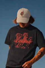 Gorro tipo dad hat color crudo con visera curva, bordado frontal de una rosa roja y texto en cursiva.