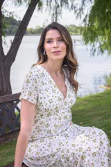 Vestido largo blanco con estampado de flores amarillas, escote en V, mangas cortas y falda con volantes. Tiene aberturas laterales en la parte inferior y forro interior.