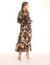 Vestido maxi de crepe estampado con flores grandes en tonos beige y marrón oscuro. Presenta escote en V con botones, mangas largas anchas con botón en los puños, y cintura con pasadores y cordón de ajuste.