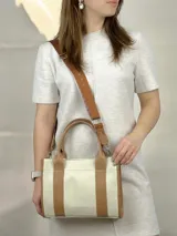 Bolso de cuero genuino en color natural, con asas cortas y correa ajustable.