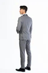 Traje de hombre de dos piezas color azul vibrante, compuesto por saco de un solo botón con solapas de pico en negro y pantalón a juego. Se complementa con camisa blanca, moño azul y pañuelo de bolsillo negro.