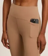 Calza deportiva color café, de microfibra ligera, tiro alto y corte ajustado. Cuenta con elástico en la cintura y tiras porta remera en la espalda.