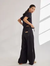 Pantalón negro de pierna ancha con tiro medio alto y pretina elastizada en la espalda. Presenta bolsillos plaque en delantera y espalda.