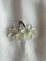 Par de aros plateados tipo argolla con dije colgante de acrílico transparente con forma de estrella de seis puntas.