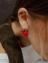 Aros colgantes plateados con dije de flor acrílica color dorado.