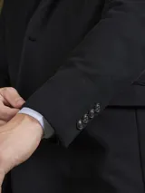 Blazer azul marino de corte clásico con solapa de muesca, cierre de dos botones y bolsillos laterales con solapa.