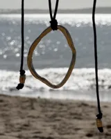 Collar con dije circular irregular de alpaca y plata 925, con hilo de algodón natural.