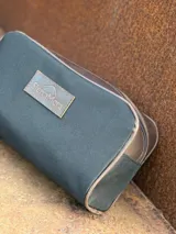Neceser de lona verde con detalles en cuero color beige y etiqueta con logo de la marca Sierra Mora.