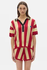 Chomba de punto calado a rayas rojas y beige, con cuello polo negro y detalle de botón en el escote.