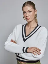Sweater blanco de tejido de punto con escote en V y rayas negras en el cuello, puños y ruedo.