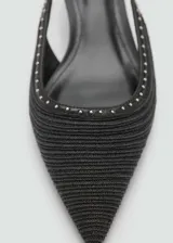 Zapato destalonado negro de tejido de fibra natural con detalle de tachuelas, punta fina, cierre de hebilla y tacón kitten.