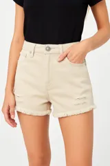 Short de jean color beige, tiro alto, con bolsillos delanteros y traseros, roturas y ruedo desflecado.