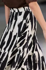 Falda midi de tiro alto confeccionada en hilatura de algodón. Detalle de pliegues en cintura y bajo evasé. Estampado abstracto en blanco y negro.