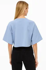 Remera cropped color rosa con cuello redondo, manga 3/4 y cierre frontal con broches.