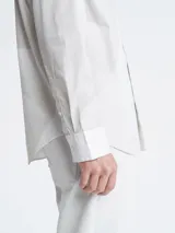 Camisa blanca de manga larga con cuello clásico y cierre con botones.