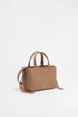 Bolso de mano Bimba y Lola modelo Chihuahua, tamaño mini, color marrón topo, fabricado en piel con piezas de metal plateado. Presenta estructura blanda, cierre con cinta de piel, logo metálico, bolsillo interior con cremallera e interior con logo grabado.