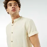 Camisa de lino color amarillo claro, de corte recto, con cuello mao, manga corta con dobladillo y cierre frontal con botones.