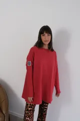 Buzo rojo de viscosa, corte amplio, cuello redondo y manga larga con parche bordado en el brazo.