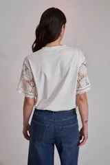 Remera blanca de algodón con mangas cortas de encaje floral.