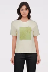 Remera color crema con estampado de flores en tonos verdes y dorados.