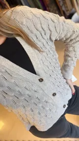 Saco de punto color gris claro con diseño de gotas en relieve, cuello en V y cierre con un botón.